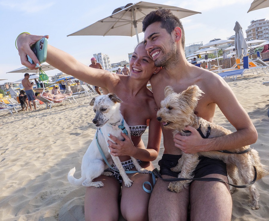 Una coppia che fa un selfie durante le loro vacanze al mare con i loro due cani